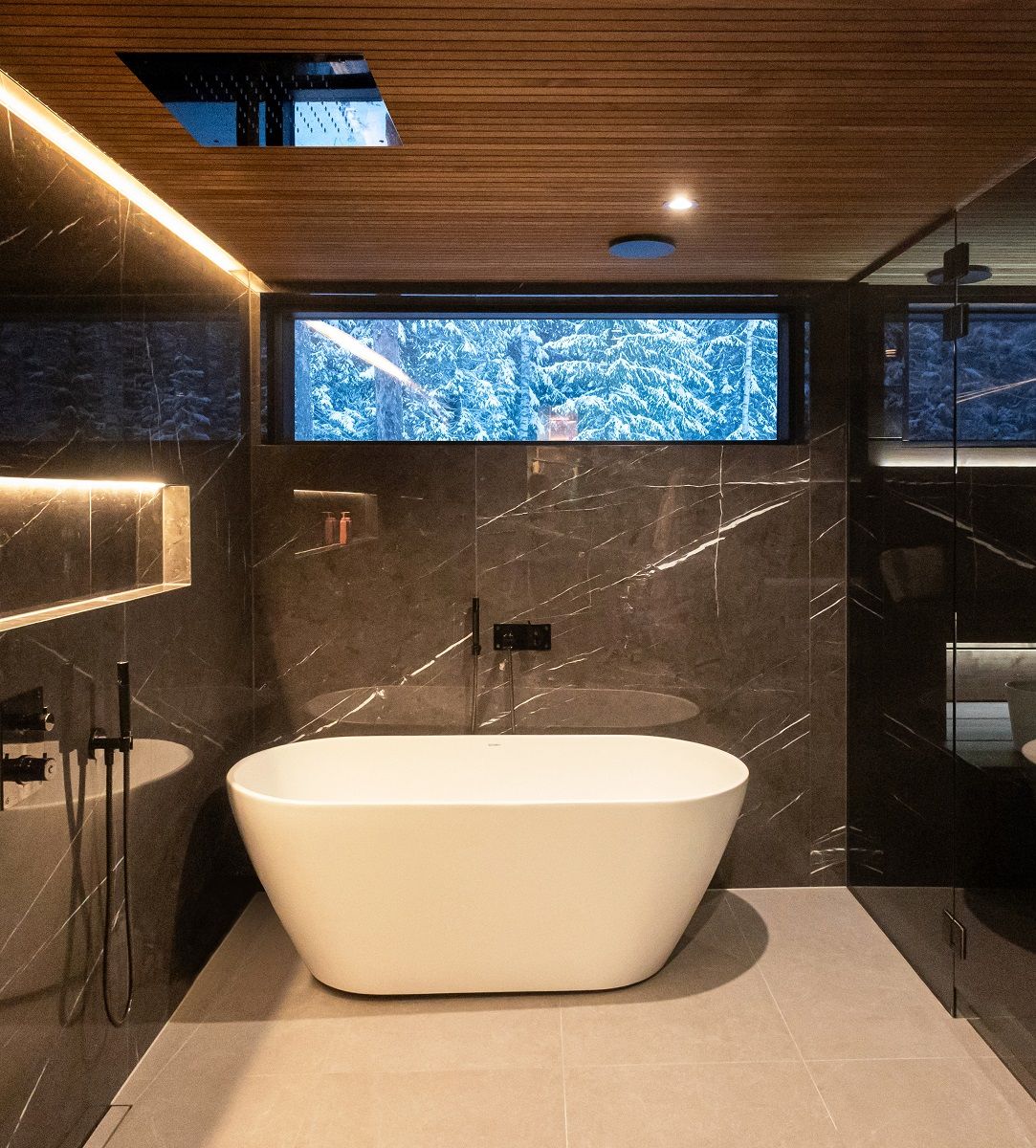 Atmospheric bathroom lighting with LED strip lighting at two heights and spotlights. Ribbons on the ceiling/wall and on the wide shampoo shelf. The spotlights blend into the ceiling and provide the necessary general lighting. The lights are colour temperature adjustable and dimmable